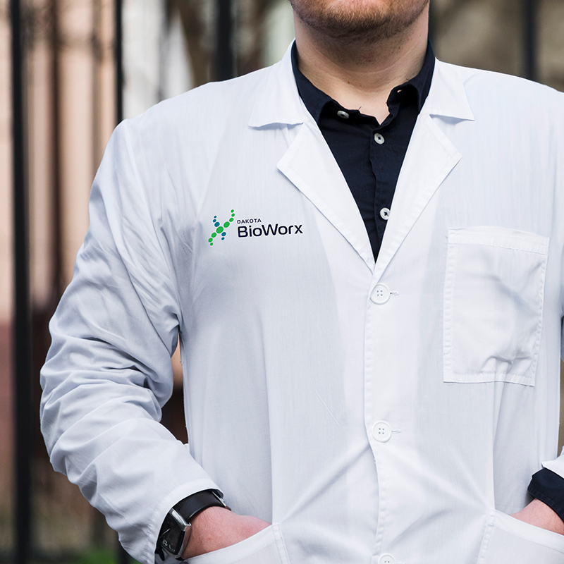 Scientist wearing a white lab coat with the Dakota BioWorx logo embroidered on the chest.